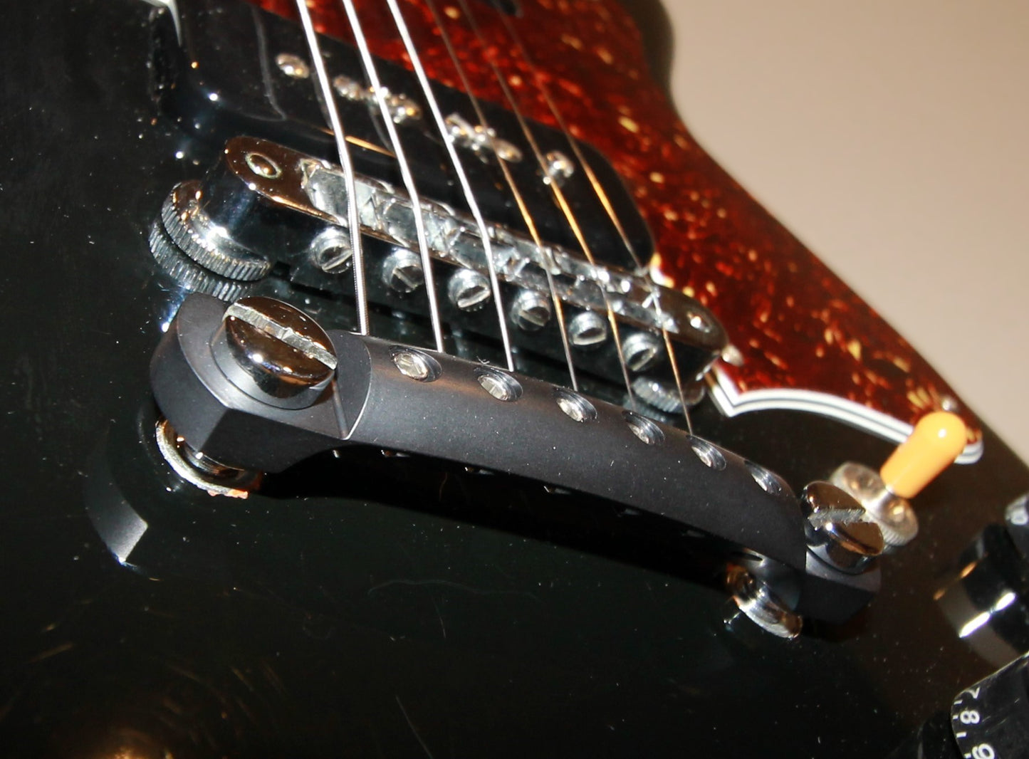 Extreme close-up of black locking aluminum stopbar tailpiece craftsmanship and rear undercut on Les Paul